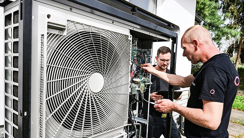 Zwei Handwerker warten eine Wärmepumpe. Die wird in Deutschland immer beliebter.
