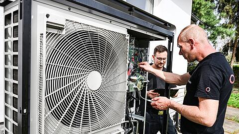 Zwei Handwerker warten eine Wärmepumpe. Die wird in Deutschland immer beliebter.