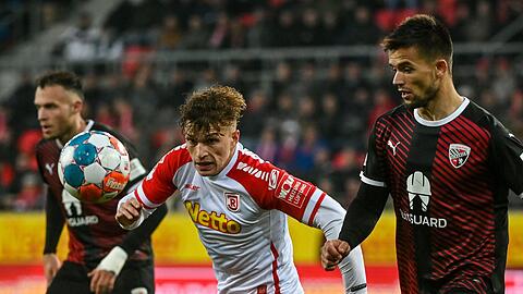 David Otto von Regensburg (M) und Visar Musliu (r) von Ingolstadt kämpfen um den Ball.