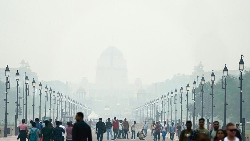 Menschen auf einer in Smog gehüllten Straße in Neu Delhi. (Archivbild)