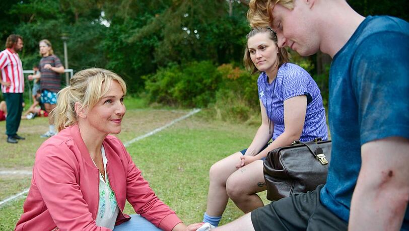 "Praxis mit Meerblick: Treffer ins Gl&uuml;ck": Nora Kaminski (Tanja Wedhorn, l.) ist zur Stelle, nachdem sich ihr Sohn Kai Kaminski (Lukas Zumbrock, r.) beim Fu&szlig;balltraining mit Trainerin Julia Fechner (Lena Schmidtke, M.) das Knie verletzt hat.