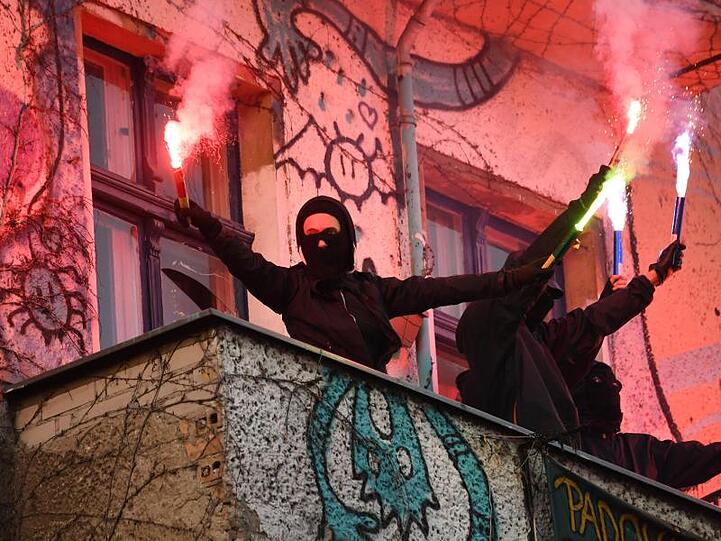 Unterstützer der linksradikalen "Revolutionären 1. Mai-Demonstration" stehen mit Pyrotechnik in den Händen auf einem Balkon in Berlin-Friedrichshain.