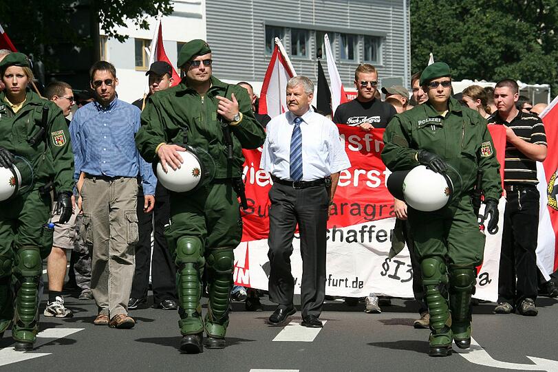 Der frühere NPD-Funktionär Ralf Wohlleben (l. mit Sonnebrille) flankiert von Polizisten, aufgenommen am 18.08.2007 während einer NPD-Demonstration in Jena, in der Mitte der damalige NPD-Parteichef Udo Voigt