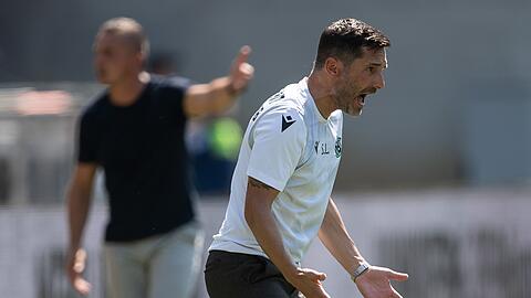Hannovers Trainer Stefan Leitl (r) und Regensburgs Trainer Mersad Selimbegovic stehen am Spielfeld.