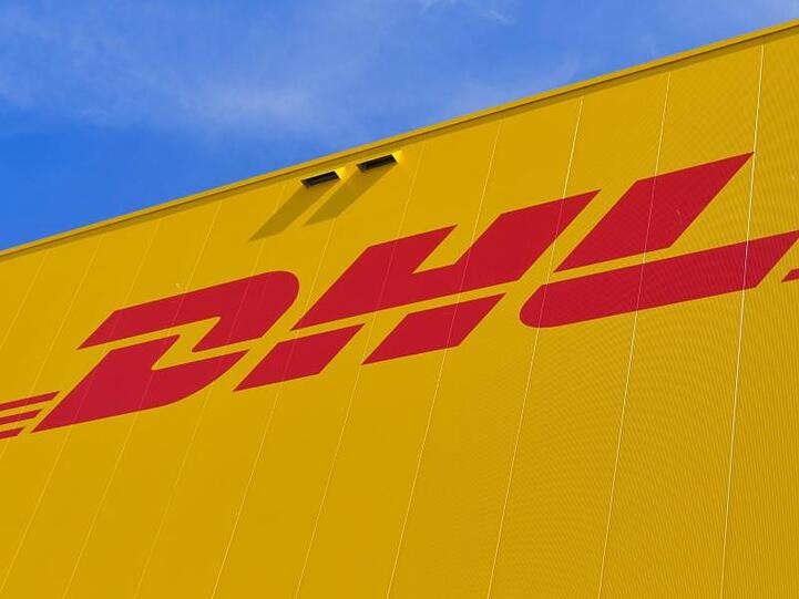 Das Logo des Paketdienstes DHL auf der Fassade eines Paketzentrums. Foto: Patrick Pleul/dpa-Zentralbild/ZB/Symbolbild