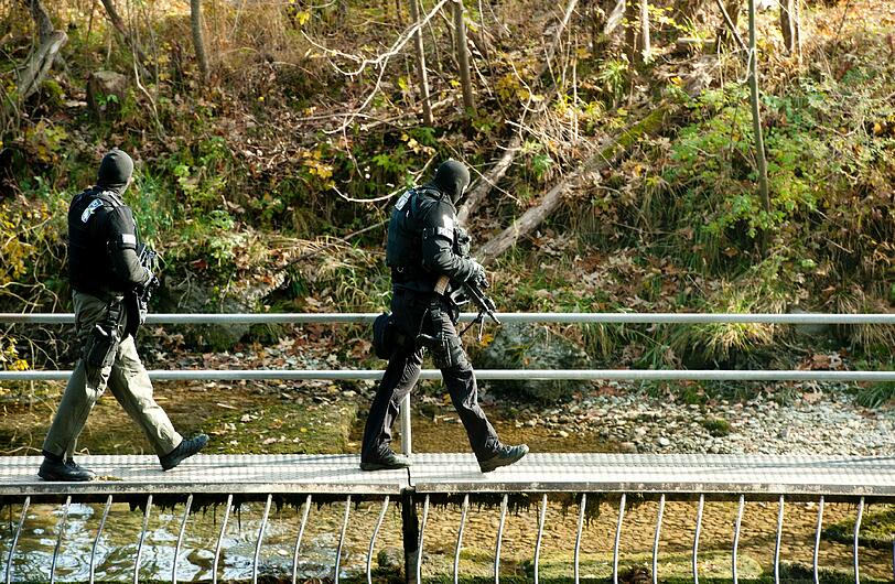 Zwei schwer bewaffnete Polizeibeamte des Spezialeinsatzkommandos (SEK) durchsuchen das Ufer des Eiskanals am Lech in Augsburg.