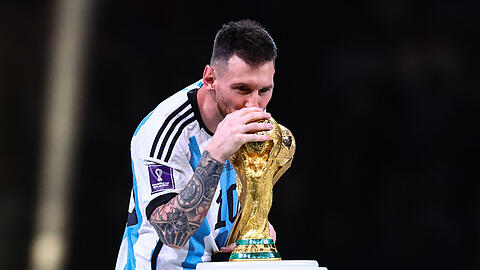 Argentiniens Lionel Messi küsst bei seiner Verleihung des "Golden Ball Award" den Weltmeisterpokal.
