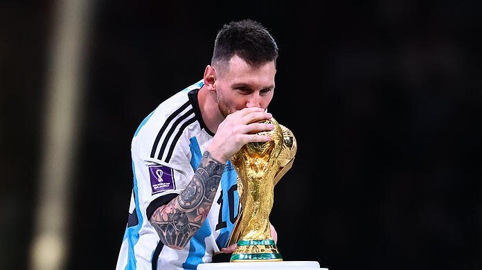 Argentiniens Lionel Messi küsst bei seiner Verleihung des "Golden Ball Award" den Weltmeisterpokal.