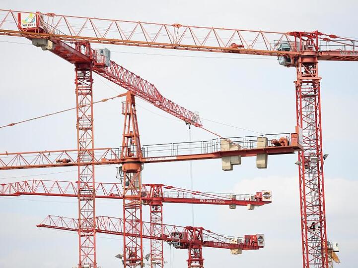 Dicht an dicht stehen Baukräne auf einer Baustelle. Foto: Arne Dedert/dpa/Archivbild