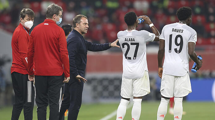 Hansi Flick spricht an der Seitenlinie mit David Alaba (2.vr) und Alphonso Davies.