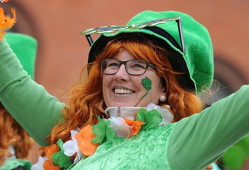 Eine Teilnehmerin der St. Patrick's Day-Parade winkt den Zuschauern am Straßenrand zu.