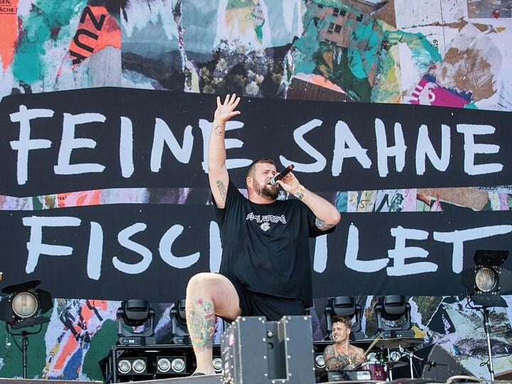 Jan "Monchi" Gorkow (M.), Sänger der deutschen Punkband "Feine Sahne Fischfilet", steht auf der Bühne und singt. Foto: Daniel Karmann