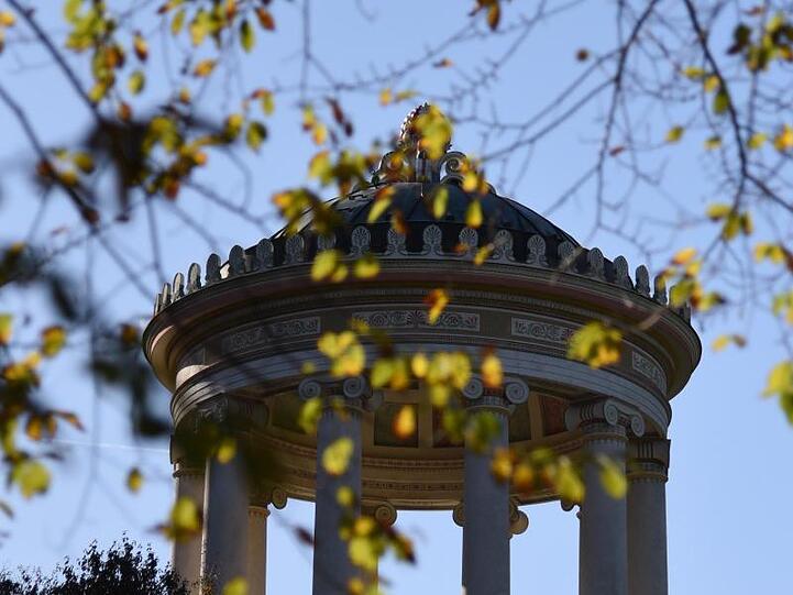 Hinter herbstfarbenen Zweigen ist der Monopteros im Englischen Garten in München (Bayern) zu sehen. Foto: Amelie Geiger/Archivbild