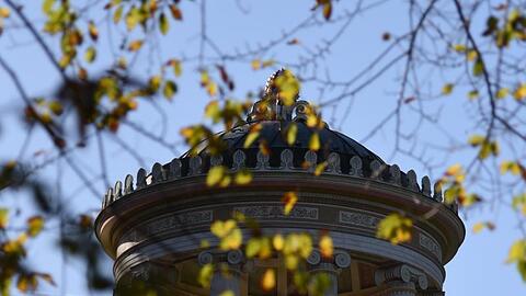 Hinter herbstfarbenen Zweigen ist der Monopteros im Englischen Garten in München (Bayern) zu sehen. Foto: Amelie Geiger/Archivbild