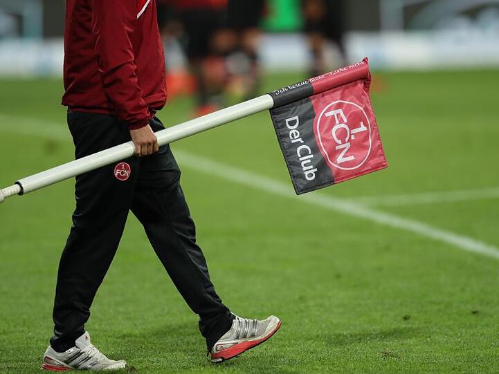 Ein Helfer trägt eine Eckfahne mit dem Logo des 1. FC Nürnberg. Foto: Daniel Karmann/Archiv