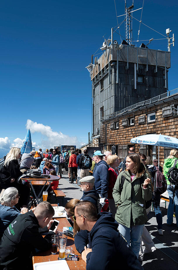 Zugspitze-Besucher genie&szlig;en die Sonne vor dem M&uuml;nchner Haus, Deutschlands h&ouml;chster H&uuml;tte.