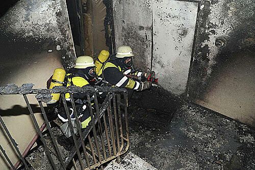 Feuwerwehrler untersuchen die Brandschäden in einem Pasinger Wohnhaus