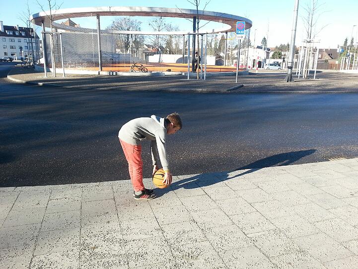 Als ich das Photo gemacht habe, flog plötzlich der Basketball über den Zaun. Hier wäre eine Abdeckung nach oben unbedingt notwendig weil: Erstens die Kinder dem Ball nachlaufen und hier Busse und Autos fahren und zweitens der Ball jemanden treffen könnte.