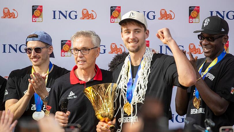 Trainer Gordon Herbert (2.v.l) steht beim Empfang neben Franz Wagner mit der Trophäe und Daniel Theis.