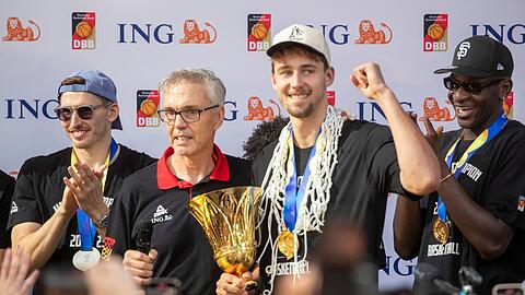 Trainer Gordon Herbert (2.v.l) steht beim Empfang neben Franz Wagner mit der Trophäe und Daniel Theis.