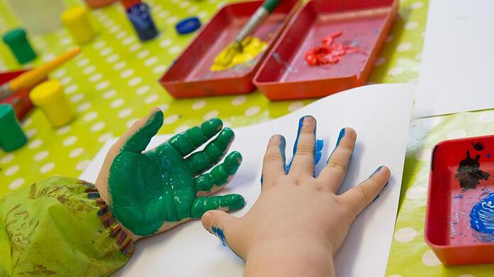 Ein Kind spielt mit Fingerfarben im Kindergarten der Katholischen Kirchengemeinde Heilig-Geist in Würzburg (Bayern). Foto: Daniel Karmann/Archiv