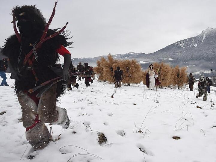 Ein Krampus (l) läuft in Berchtesgaden den Buttnmandl und dem Nikolaus voraus. Foto: Angelika Warmuth/dpa/Archivbild