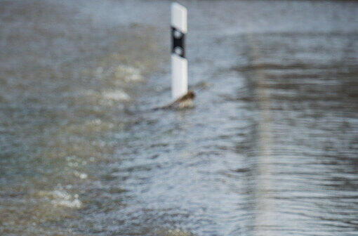 Das Wasser des Roten Mains fließt am 24.12.2012 über eine wegen Hochwasser gesperrte Straße in Heinersreuth (Bayern).