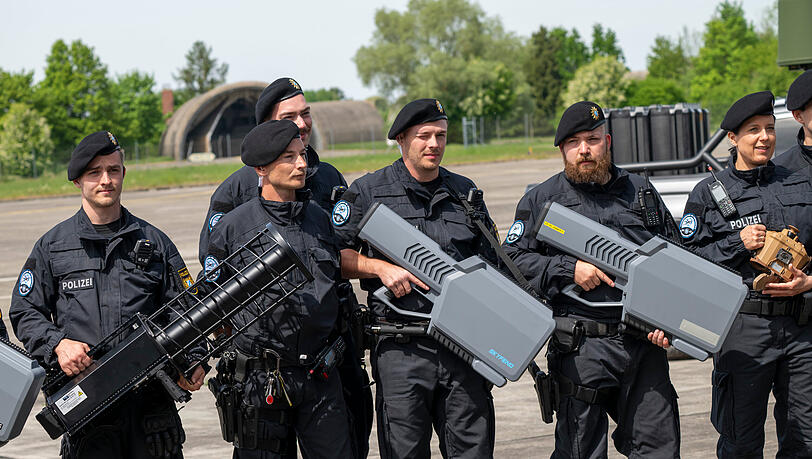 Polizisten halten w&auml;hrend der Er&ouml;ffnung des Drohnenkompetenz- und -abwehrzentrum diverse Drohen-Abfangger&auml;te in den H&auml;nden.