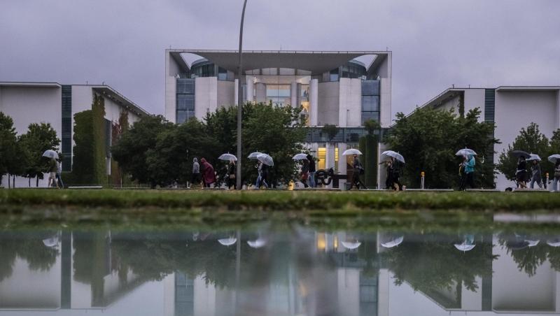 Kühl und grau: Eine Gruppe mit Regenschirmen geht am Bundeskanzleramt vorbei. Kühl und grau: Eine Gruppe mit Regenschirmen geht am Bundeskanzleramt vorbei.