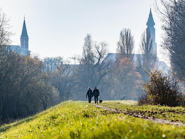 Spaziergänger sind auf einem Donaudamm in Straubing unterwegs. Foto: Armin Weigel/dpa/Archivbild