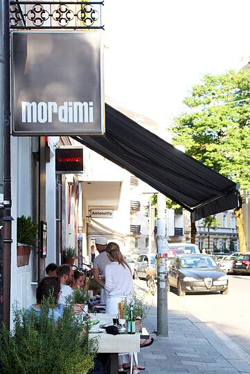 Ein paar Plätze gibt es auch auf der Terrasse zur Westermühlstraße. Hier geht es nicht ganz so quirlig zu wie etwa am Gärtnerplatz, die Leute beobachten das gemächlichere Viertel-Leben.