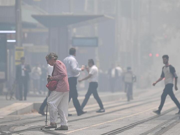 Fußgänger überqueren die in Rauch gehüllte George Street im Stadtzentrum von Sydney.