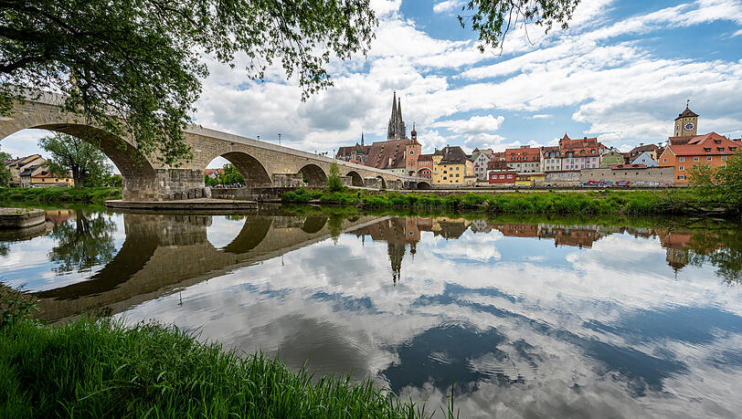 Regensburgs Altstadt mit Steinerner Br&uuml;cke und den T&uuml;rmen des 750 Jahre alten Doms, gespiegelt im Wasser der Donau.