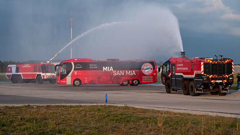 Bei der Rückkehr am Sonderflughafen Oberpfaffenhofen werden die Bayern-Stars immerhin von der Feuerwehr empfangen. Statt der Weißbierdusche müssen die Münchner mit Wasser Vorlieb nehmen.