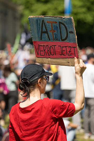 Eine Demonstrantin hält ein Plakat mit der Aufschrift "AfD - Verbot Jetzt" .