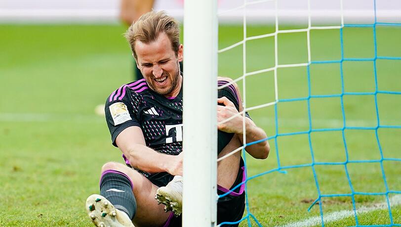 Harry Kane von München sitzt mit schmerzverzerrtem Gesicht auf dem Rasen.
