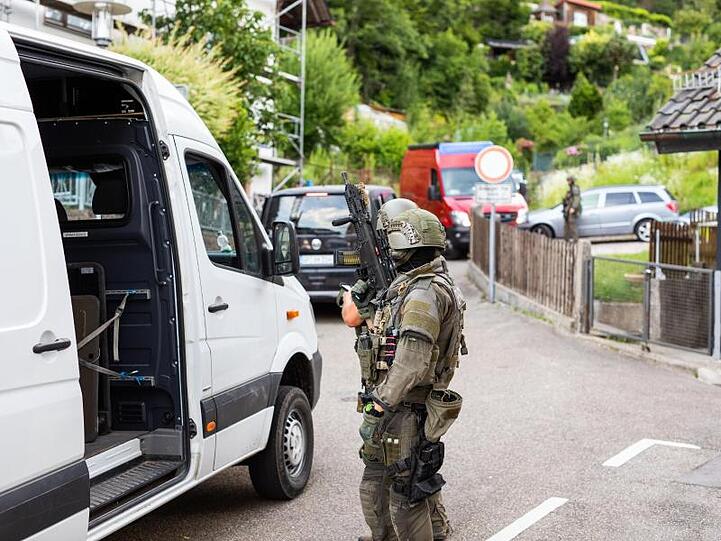 Polizisten des Sondereinsatzkommandos SEK stehen in einem Wohngebiet am Rand der Ortschaft Oppenau.