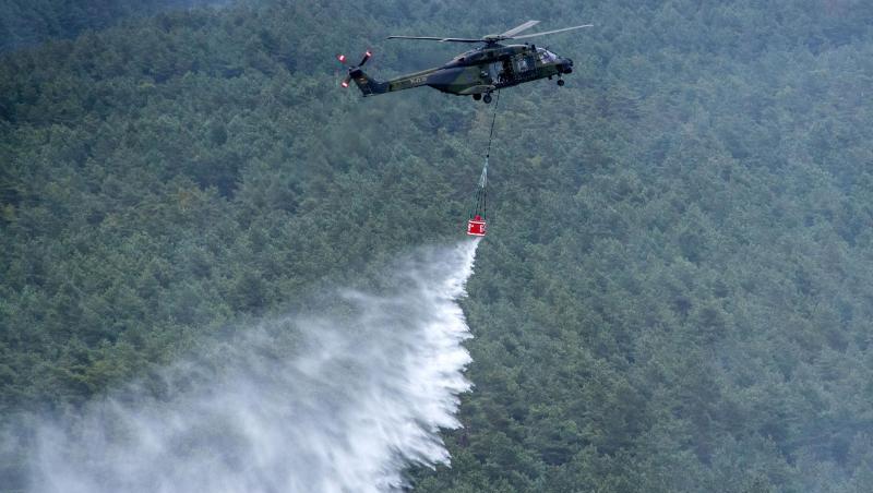 Ein Hubschrauber der Bundeswehr vom Typ NH90 mit einem Löschwasser-Behälter wirft über einer Brandstelle Löschwasser ab. Ein Hubschrauber der Bundeswehr vom Typ NH90 mit einem Löschwasser-Behälter wirft über einer Brandstelle Löschwasser ab.