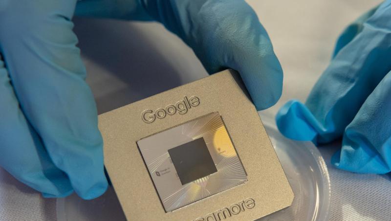 Ein Google-Quantenprozessor "Sycamore" wird mit blauen Handschuhen in die Kamera gehalten.