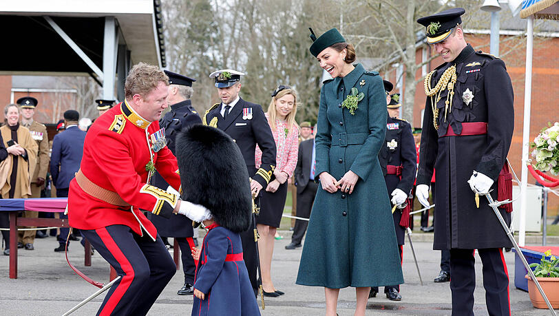 Schwupps, der Kopf des kleinen Mädchens ist komplett in der Bärenfellmütze verschwunden. Herzogin Kate und Prinz William amüsieren sich sichtlich über die Aktion.