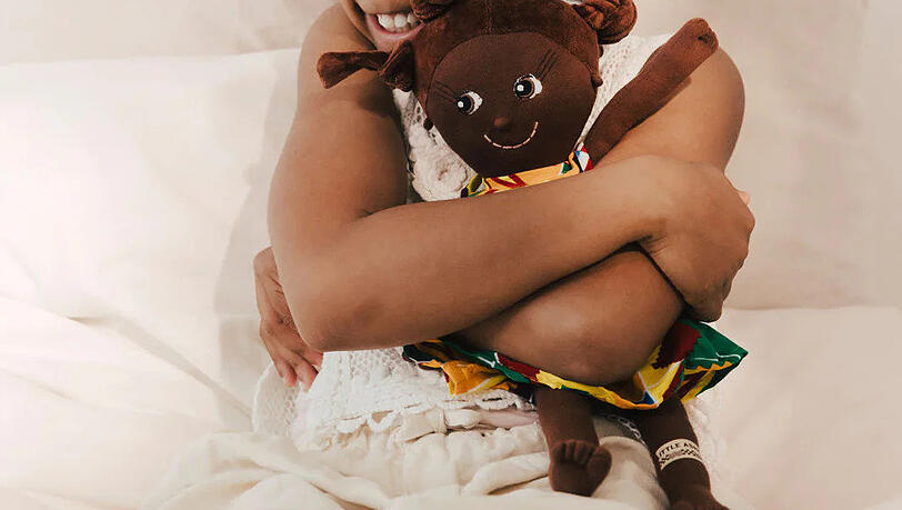 Ein Mädchen mit einer Little Ashé-Puppe. Ein Mädchen mit einer Little Ashé-Puppe.