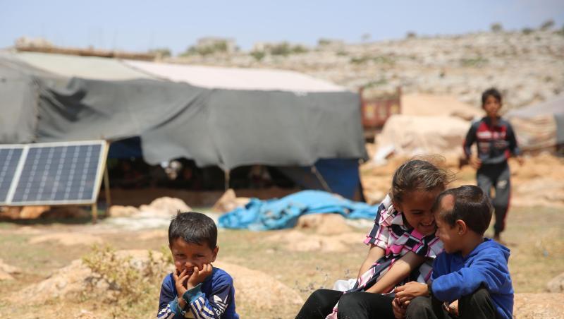 Geflüchtete Kinder sitzen in einem Flüchtlingslager nordwestlich von Aleppo auf einem Stein.