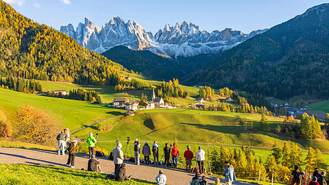Das Dorf St. Magdalena im Villn&ouml;&szlig;tal in S&uuml;dtirol vor der Geislergruppe &ndash; mit Besuchern auf der Suche nach dem besten Standort f&uuml;rs Foto.