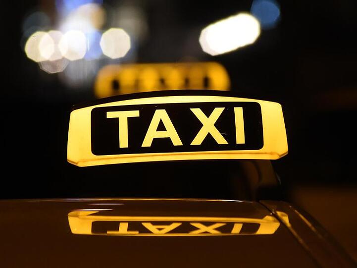 Das Dachschild eines Taxis leuchtet bei Dunkelheit. (Symbolbild)
