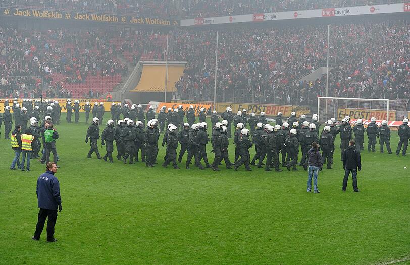 05.05.2012 Mit dem Schlusspfiff stürmen Hooligans des 1. FC Köln nach der 1:4-Niederlage gegen Bayern München den Platz und können nur von einem massiven Polizeiaufgebot in Schach gehalten werden. Zuvor waren bereits auf der Kölner Fantribüne Rauchbomben und Bengalische Feuer gezündet worden.