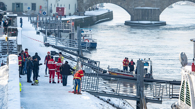 Rettungskräfte stehen am Ufer der Donau nahe der Steinernen Brücke.