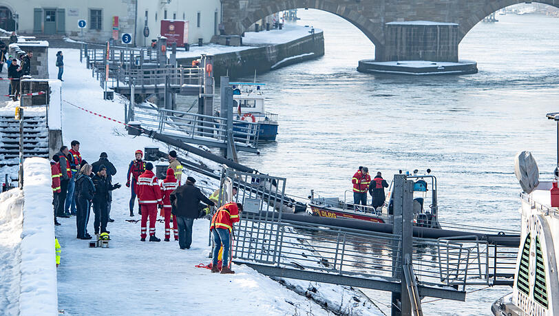 Rettungskräfte stehen am Ufer der Donau nahe der Steinernen Brücke. Rettungskräfte stehen am Ufer der Donau nahe der Steinernen Brücke.