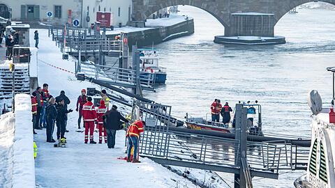 Rettungskräfte stehen am Ufer der Donau nahe der Steinernen Brücke.