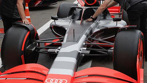 Teammitglieder schieben den neuen Rennwagen von Audi auf der Rennstrecke Spa-Francorchamps.