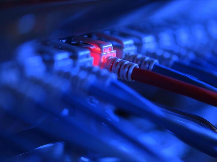 Ein Netzwerkkabelstecker leuchtet in einer Netzwerkzentrale rot. Foto: Felix Kästle/dpa/Archivbild